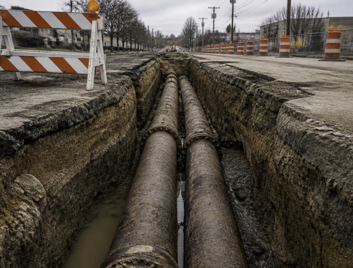 Cast iron water mains exposed in an open street trench during replacement work